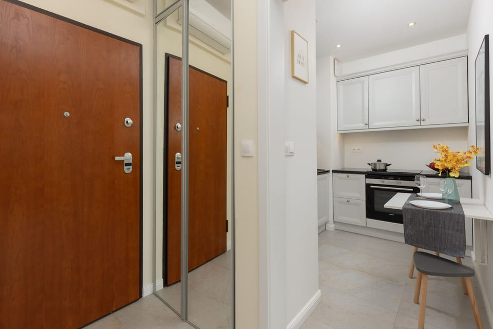 A hallway leading to the apartment’s main rooms, featuring wooden doors and a modern light fixture. The space is clean and organized.