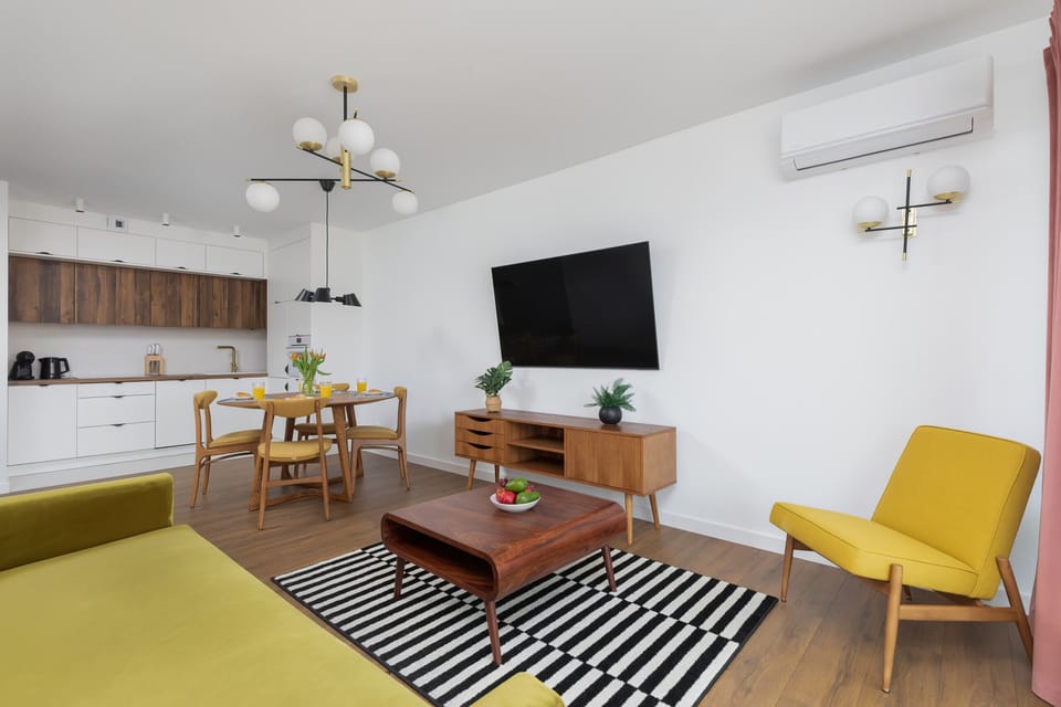 A view of the combined living and dining space, showing a green sofa and a round wooden dining table with chairs.