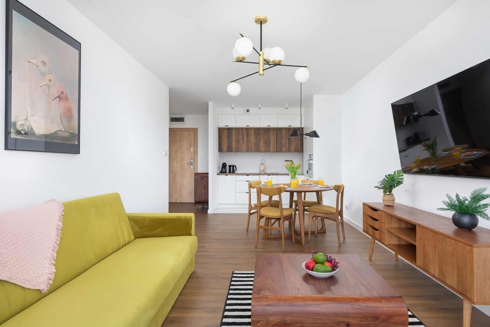 A living room with red curtains, a green sofa, and a coffee table on a striped rug.