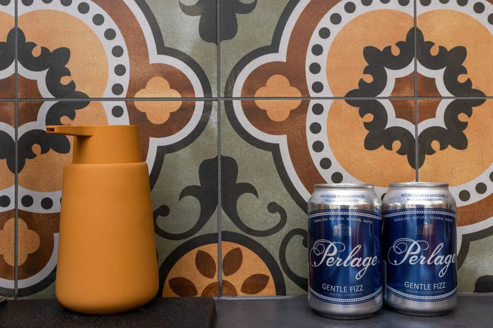 A close-up of stylish kitchen decor featuring colorful, intricate tiles and modern appliances. A cheerful mustard vase complements the design.