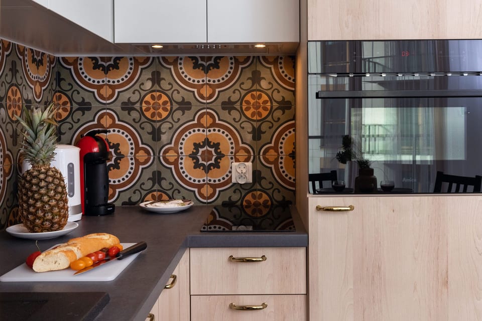 A modern kitchen with sleek wooden cabinets, a black countertop, and a vibrant tile backsplash for a stylish finish.