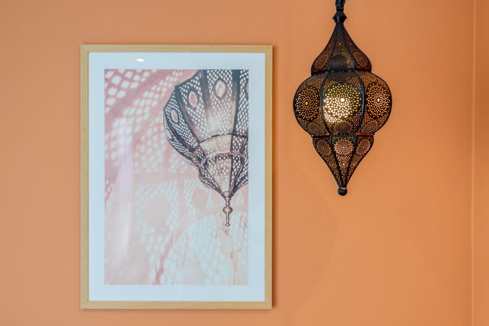 A close-up of a framed artwork on an orange wall. The minimalist decor creates a warm and contemporary aesthetic.