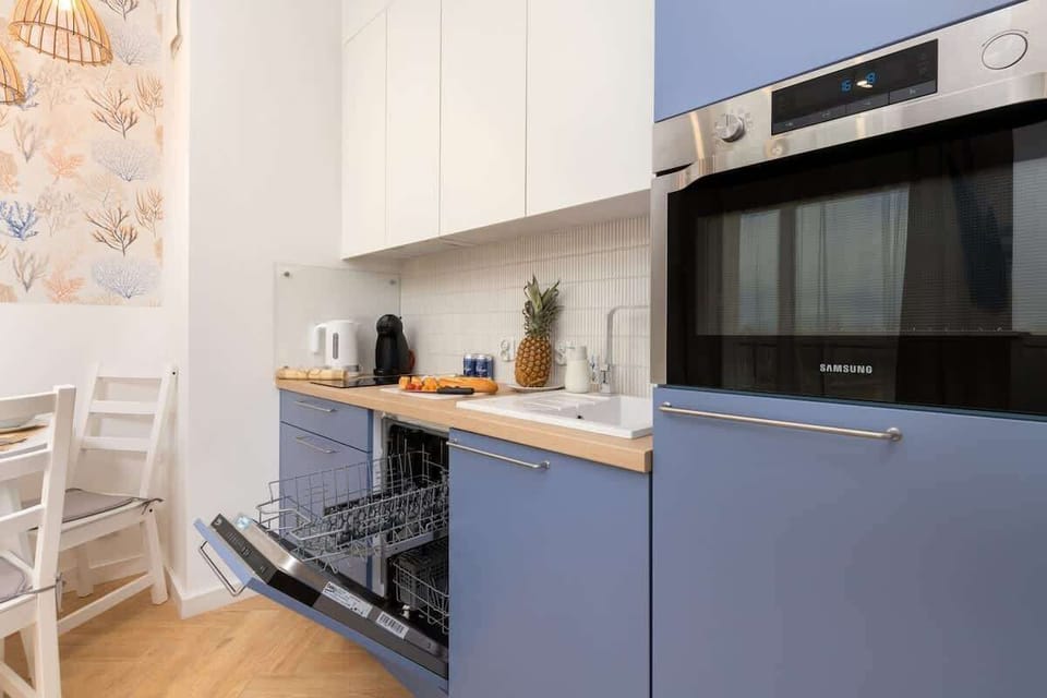 A contemporary kitchen with dark blue lower cabinets, a built-in oven, and a microwave.

