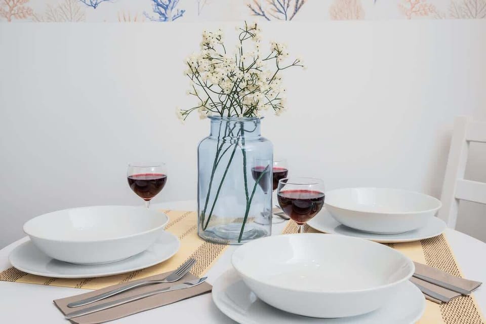 A dining table set with plates, glasses, and a vase of flowers, indicating a dining area.

