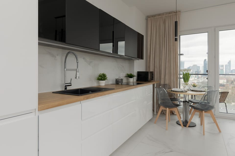 A contemporary kitchen with minimalist white cabinets, a black backsplash, and wooden countertops. The layout is sleek and ideal for cooking enthusiasts.