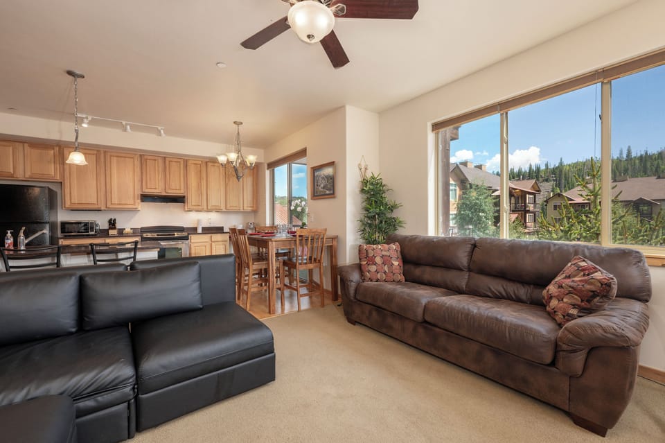 Relax in your spacious living room with leather seating while enjoying stunning mountain views through oversized windows.