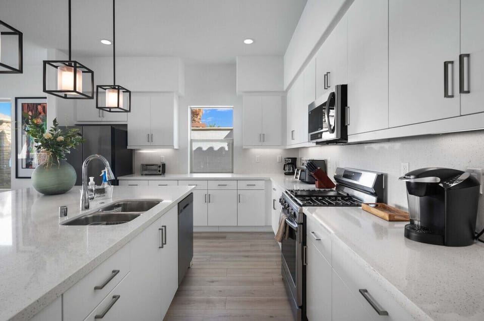 Sleek kitchen w/ stainless appliances, ample counter space & pendant lighting