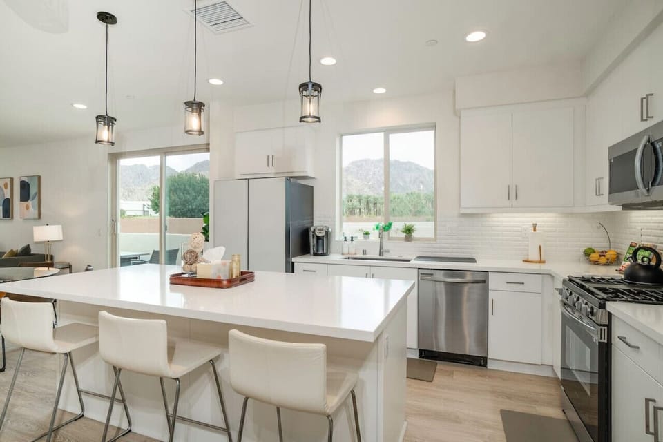 Modern kitchen w/ large island seating & bright windows overlooking the yard