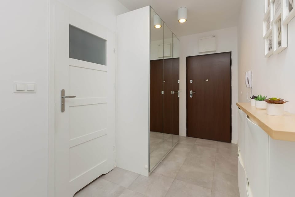 A clean, bright hallway with polished floors, wooden doors, and simple decor.