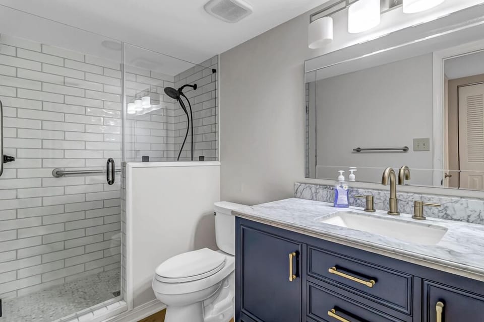 - Step into this sleek bathroom featuring a subway tiled glass shower and modern black fixtures
- Enjoy a navy sink vanity with quartz counters and elegant lighting
- Fresh, polished space to start or end your day in comfort