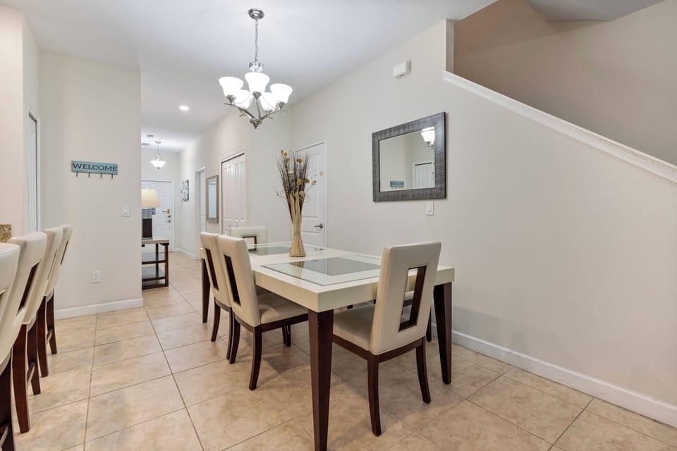 Enjoy a bright dining area with a sleek glass-top table and stylish beige chairs, perfect for sharing meals and laughter. The warm tiled floor and soft lighting create a cozy atmosphere for memorable gatherings.