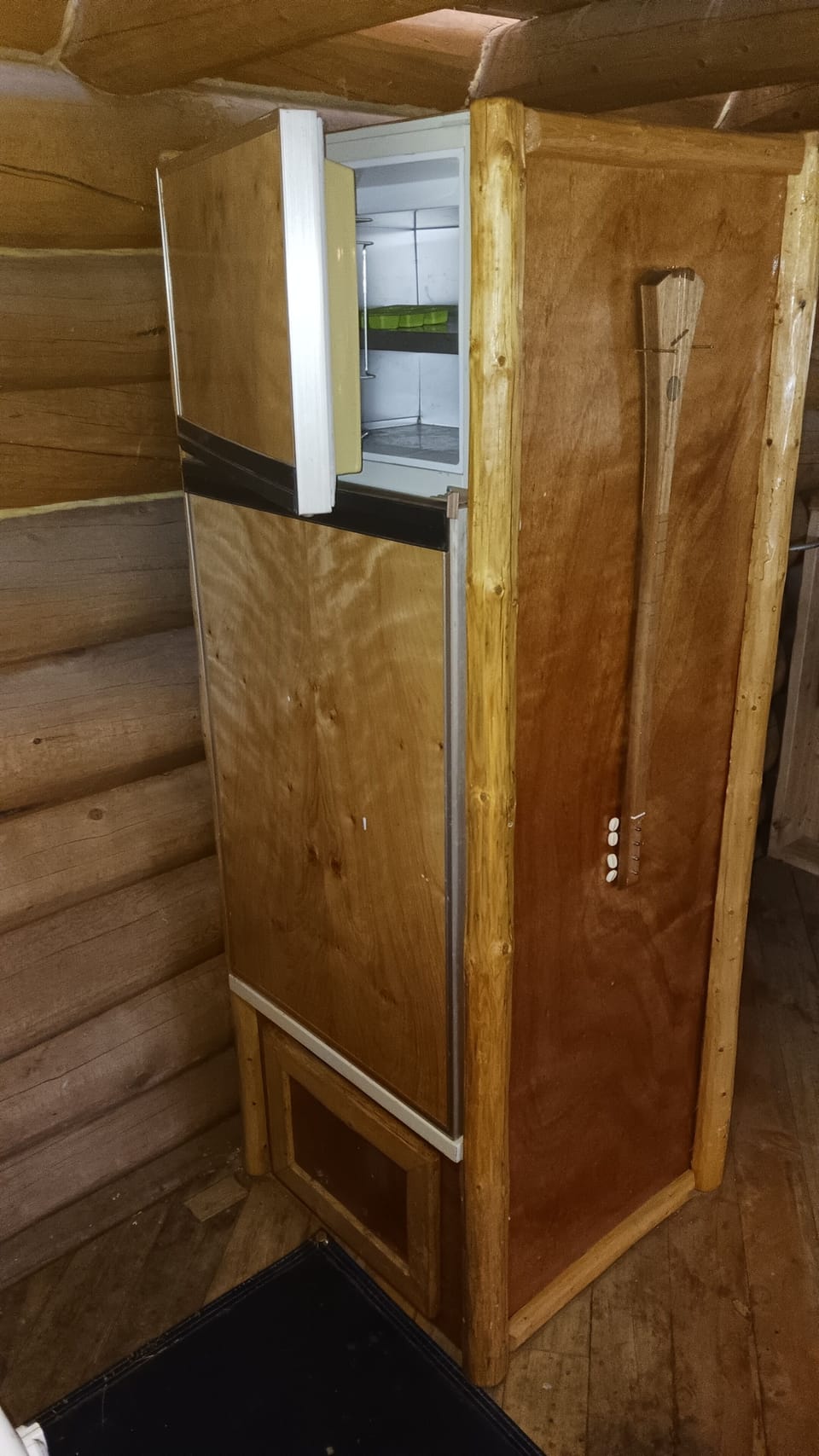 Small freezer above refrigerator, and  open-to-the-outside winter ice box below.