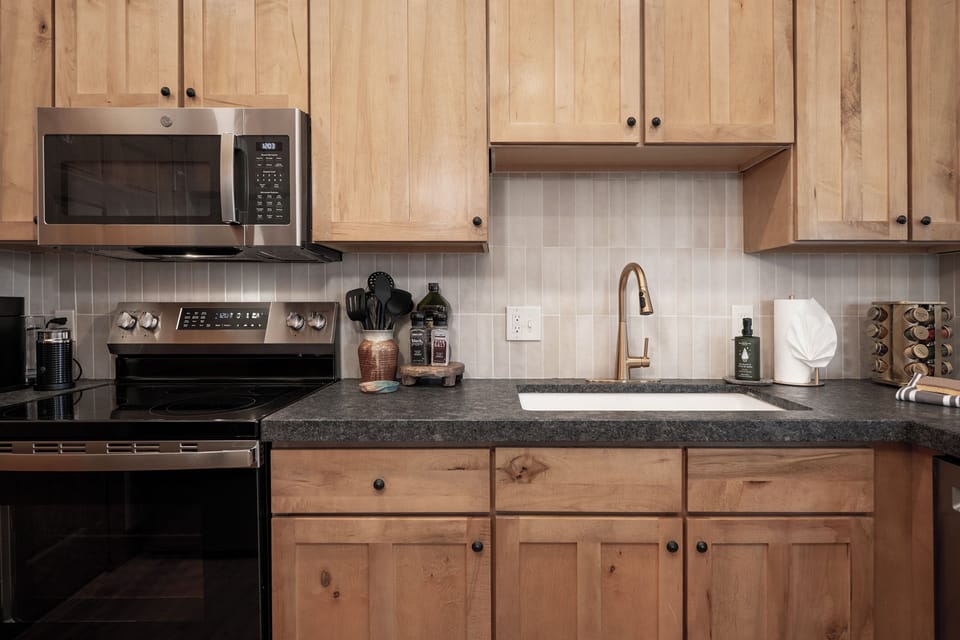 Modern kitchen with upgraded appliances, wood cabinetry, and granite