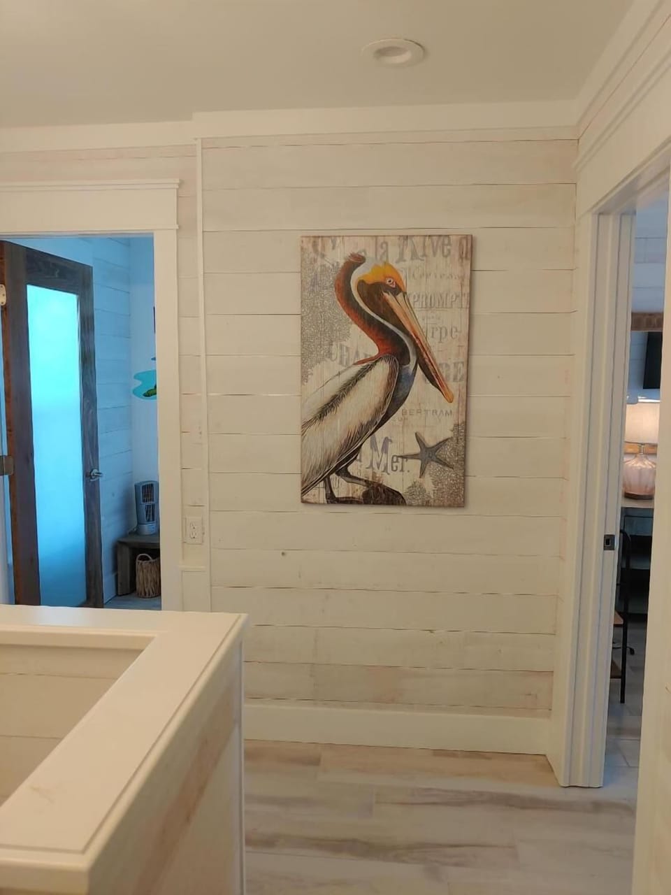 Charming coastal touches welcome you with nautical artwork adorning whitewashed shiplap walls in your bright, airy hallway.