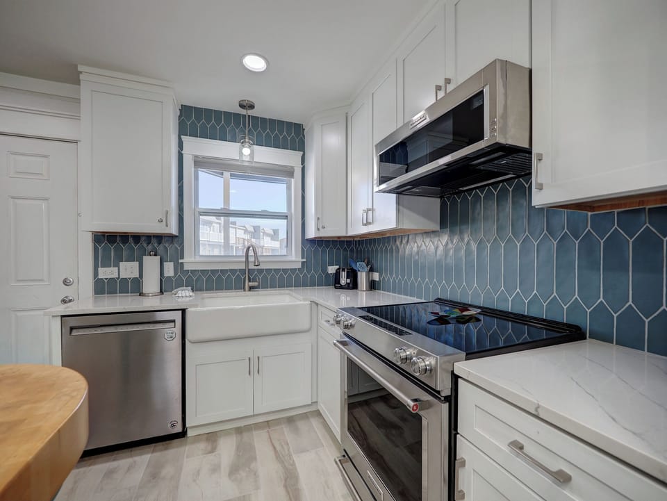 Your modern kitchen features stunning blue geometric backsplash, sleek appliances, and farmhouse sink for memorable home-cooked meals.