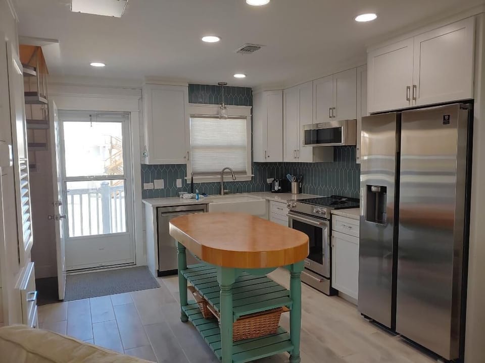 Cook your favorite meals in this bright, fully-equipped kitchen featuring modern appliances, ample counter space, and a charming island for meal prep.