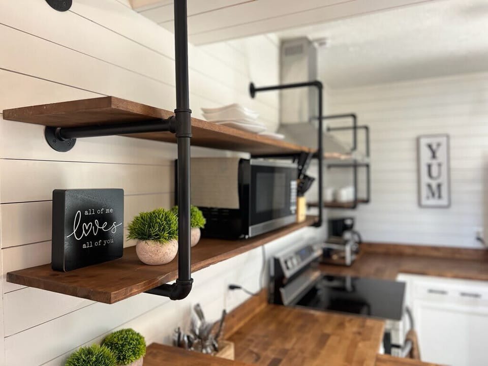 Enjoy cooking with modern appliances and rustic wooden shelves in a stylish space!