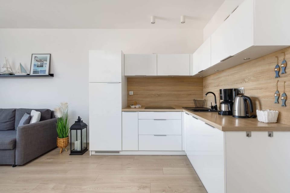 A fully equipped kitchen with white cabinets, wooden countertops, and a clean design.
