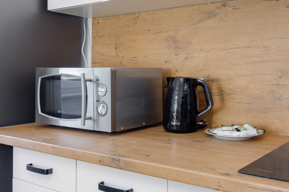 A modern microwave sits on the kitchen countertop next to a kettle. The setup is convenient and practical for daily use.