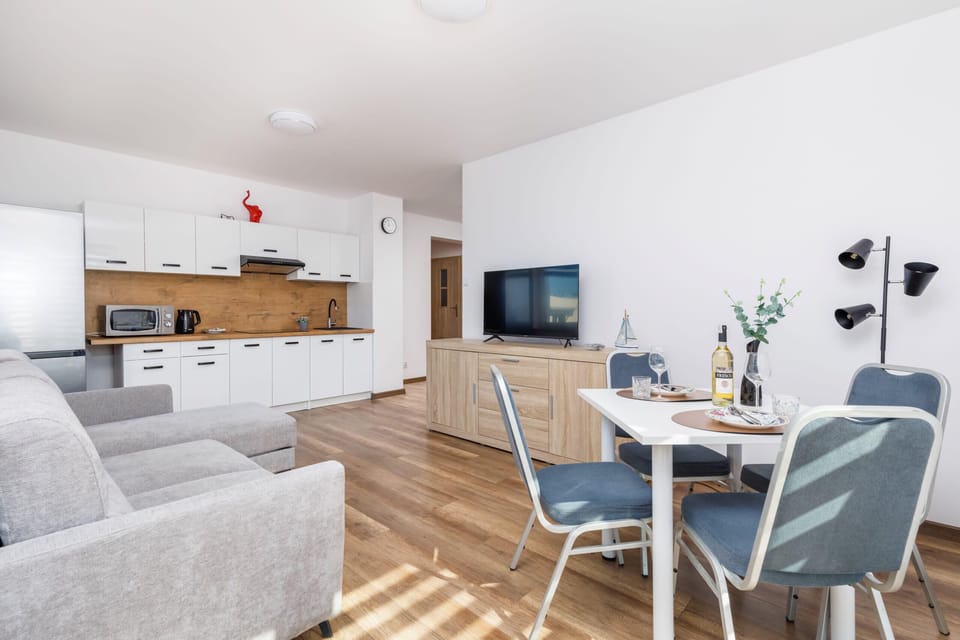A modern living area with a sectional sofa and a round dining table. The room is decorated in neutral tones for a relaxing ambiance.
