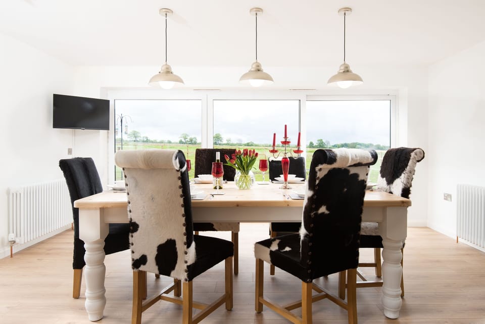 Westwood Cottage - dining table with six natural cow hide chairs and full-height sliding doors to the terrace