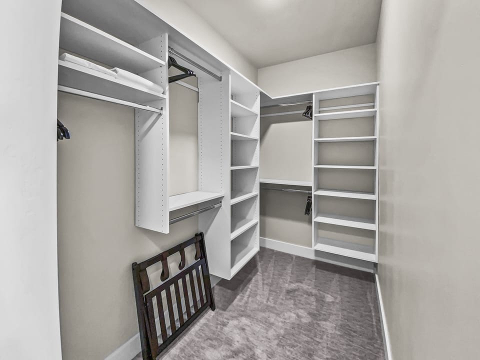 Stay organized in this expansive walk-in closet featuring custom shelving and ample hanging space. With plush carpeting and a luggage rack included, it’s the ultimate convenience for long-term stays.