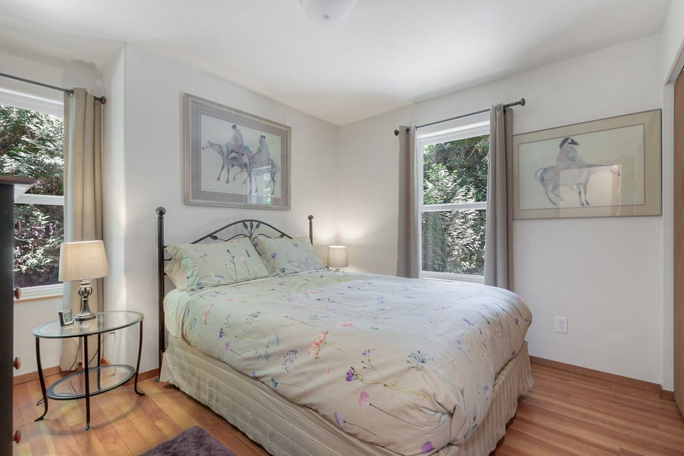 Across from the bunkroom is a bedroom with a Queen-sized bed, windows facing the front of the house (east) and the north side