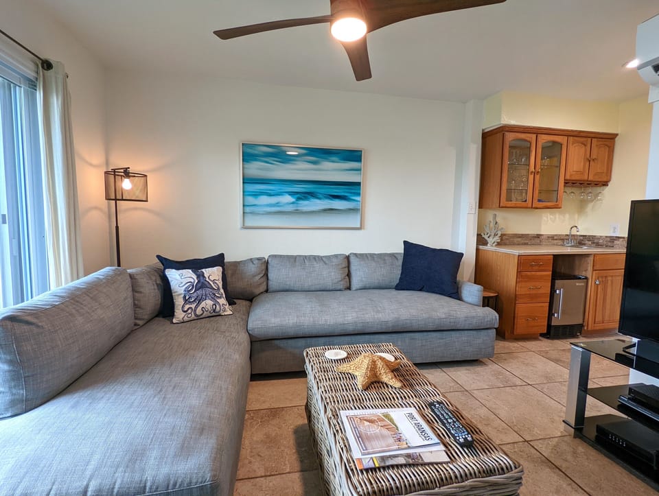 Relax on your spacious sectional sofa in this coastal-themed living space, complete with ocean artwork and fully equipped kitchenette.