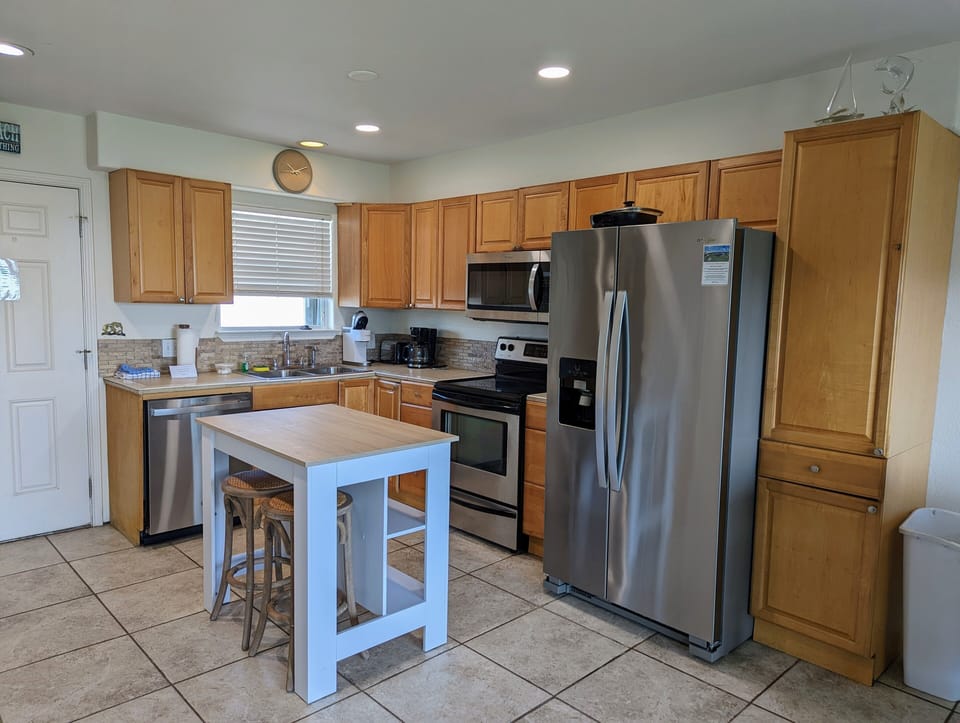 Your fully equipped kitchen awaits with stainless steel appliances, granite counters, and a charming breakfast island perfect for morning coffee.