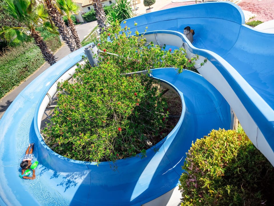 Winding water slide providing an exciting ride, nestled within lush greenery.
