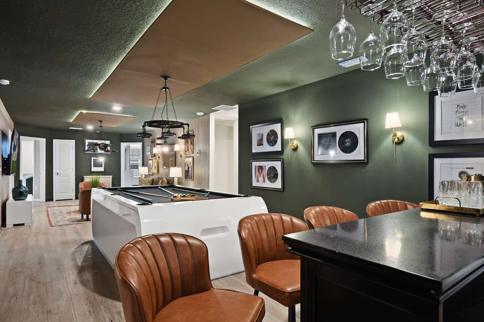 Stylish lounge with sleek pool table, vintage bar, leather chairs, and record art
