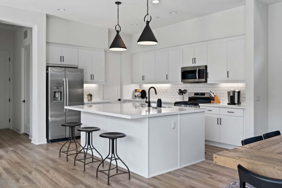 Cook & connect in the modern kitchen w/ large island, bar stools & clean white finishes