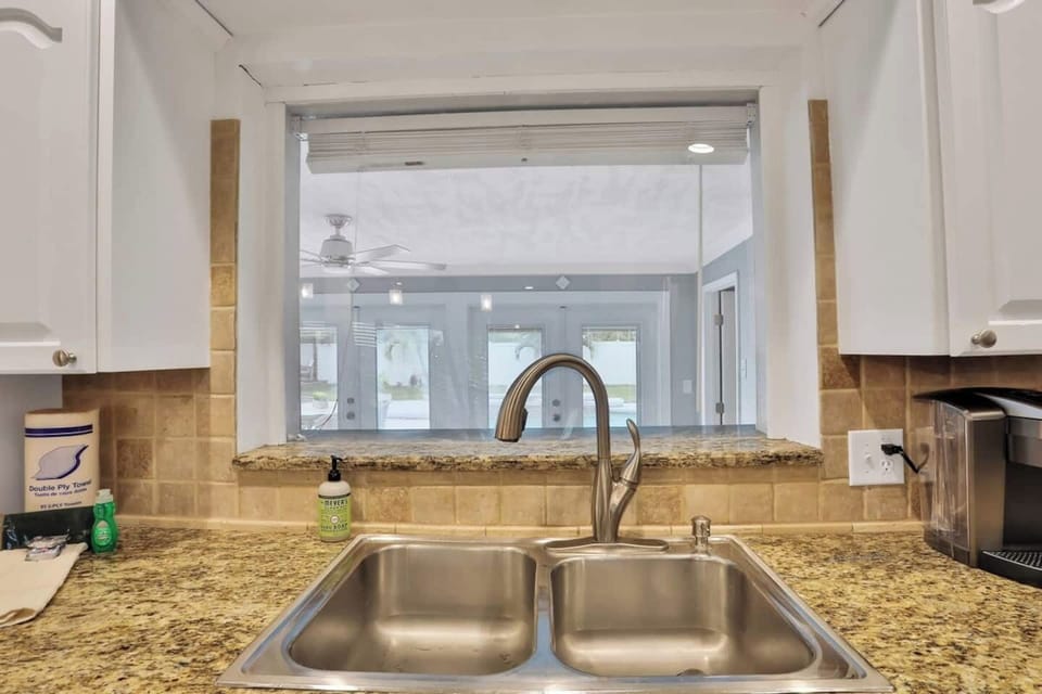 View from the kitchen sink that allows you to see into the Florida room and even check out what is going on at the pool in the huge privacy fenced back yard. 