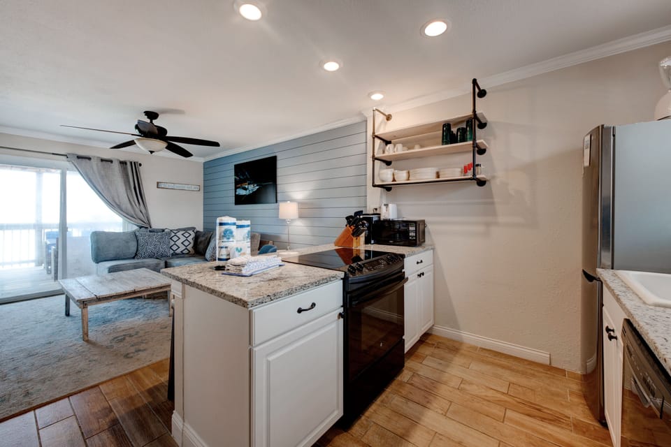 You'll love cooking in this stylish kitchen with granite counters, stainless appliances, and modern open shelving that flows seamlessly into the living area.