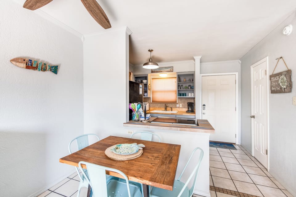 Your cozy dining space flows seamlessly into a well-equipped kitchen, complete with charming nautical touches and exposed wood beams overhead.