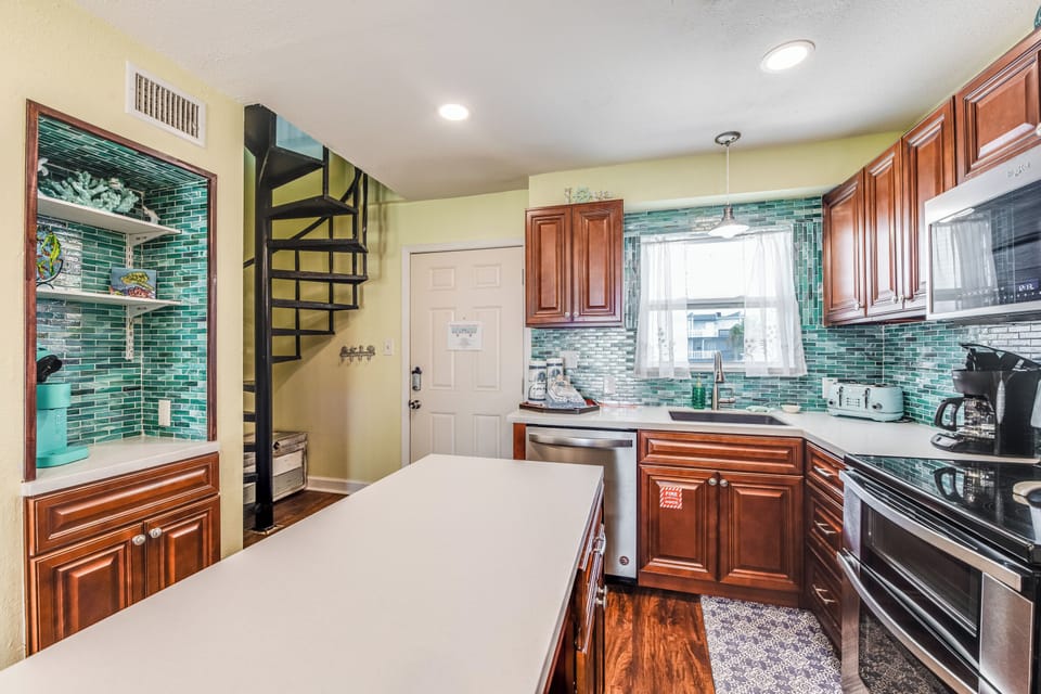 Your spacious kitchen features rich wood cabinets, stunning turquoise tile backsplash, and modern appliances for creating memorable meals.