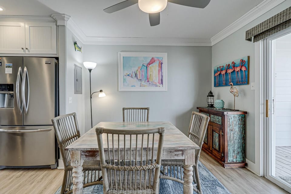 Your charming dining space features coastal artwork and vintage furnishings, perfect for memorable meals with the gentle breeze from your ceiling fan.