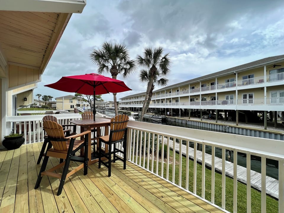 Your private balcony overlooks tranquil waterfront views with palm trees swaying gently. Enjoy morning coffee at your outdoor table.
