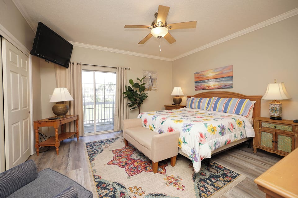 Unwind in your cheerful bedroom featuring a comfy bed with tropical linens, peaceful ocean art, and sliding door access to your private balcony.