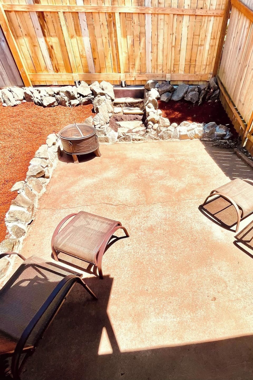 Private fenced patio with lounge chairs and a fire pit—perfect for relaxing evenings or enjoying the fresh air in a cozy, outdoor setting.