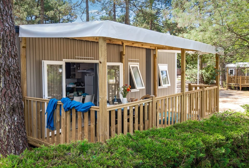 Cozy camping home with a welcoming porch, nestled in the shade of trees for a peaceful retreat.