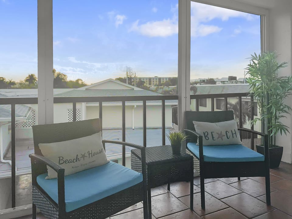 Covered balcony with cushioned seating chairs and views of the surrounding area