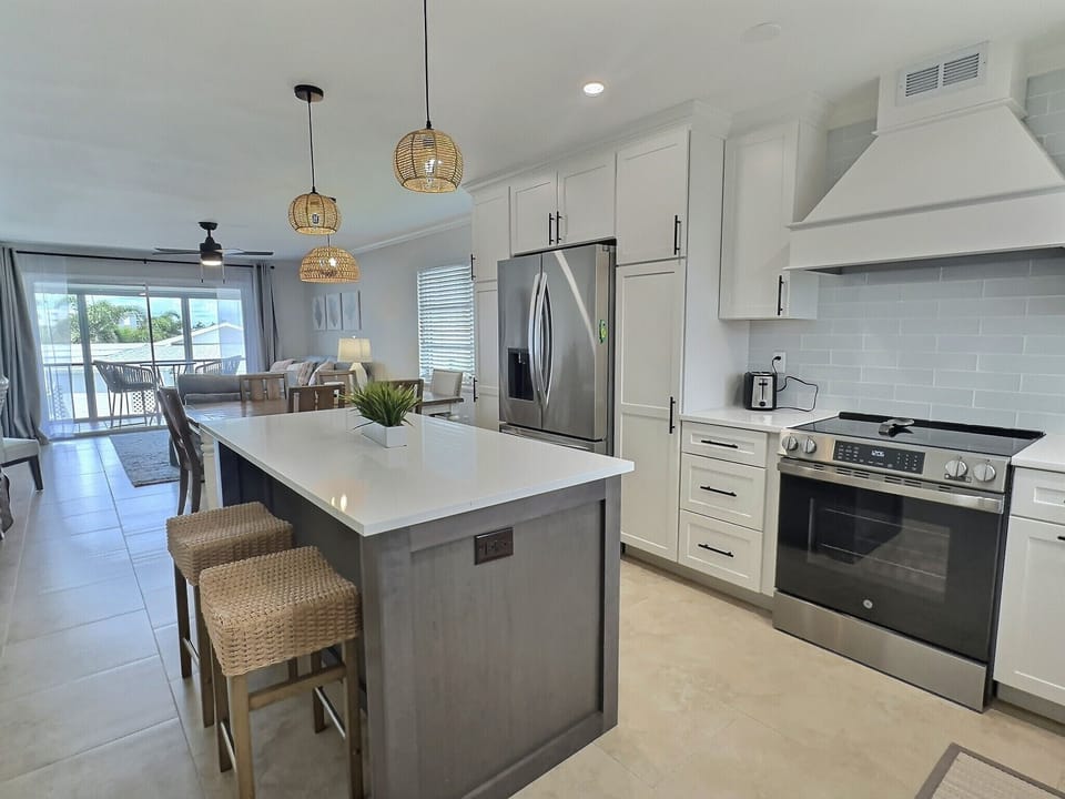 Open kitchen and dining area with island seating, stainless appliances, and access to living room