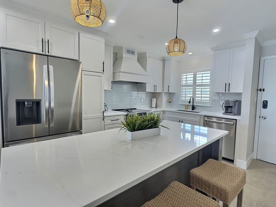 Kitchen featuring stainless steel refrigerator, island with seating, and white cabinetry