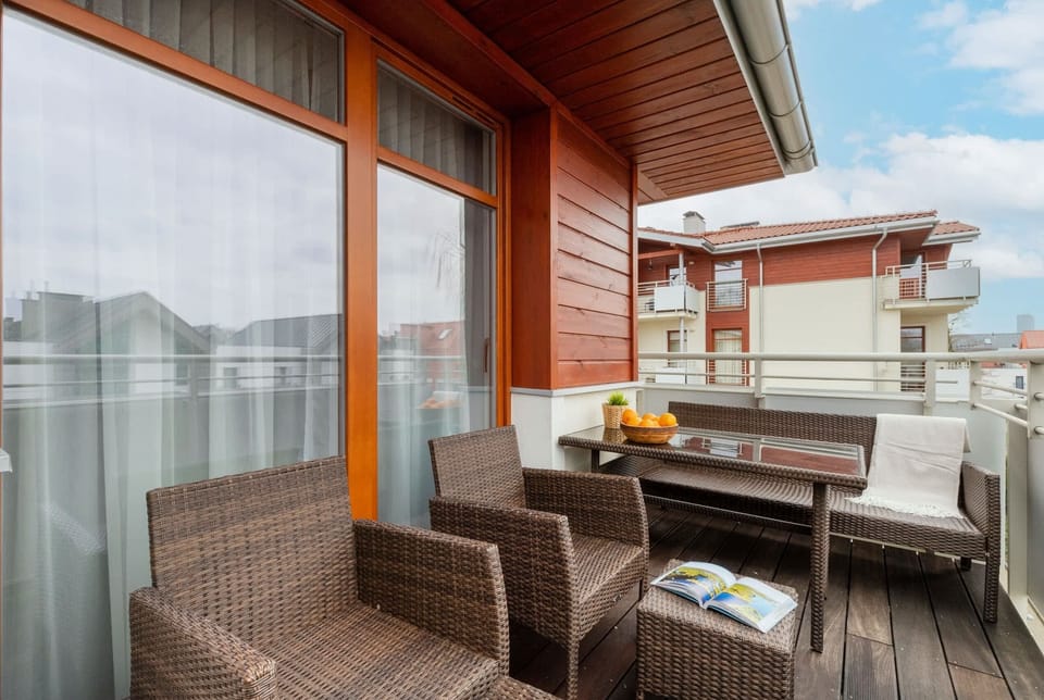 A spacious balcony with wicker furniture, offering a relaxing spot to enjoy outdoor views.