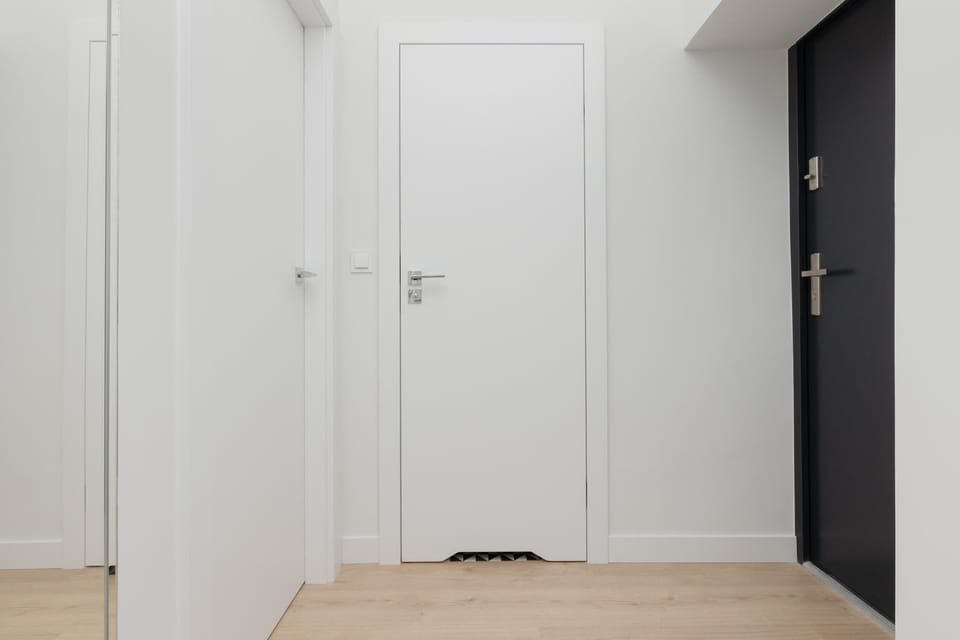 A hallway leading to the entrance, with a sleek door and clean minimalist design.
