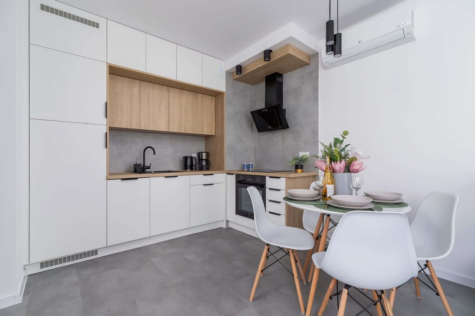 A compact kitchen and dining area featuring wooden cabinets, white countertops, and chic furniture.
