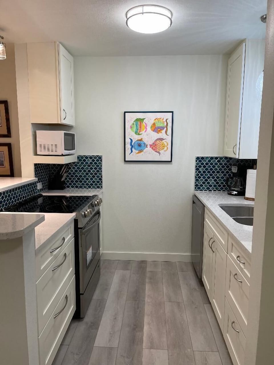 Your fully equipped galley kitchen features modern appliances and cheerful fish artwork to brighten your cooking experience.