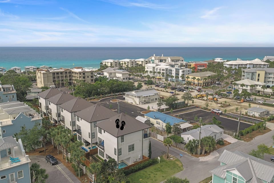 Aerial view of a coastal residential community nestled among palm trees, just steps from turquoise Gulf waters.