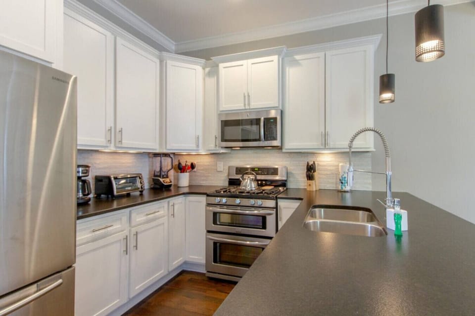 A kitchen with white cabinets, stainless appliances, and subway tile backsplash is clean and fully stocked.